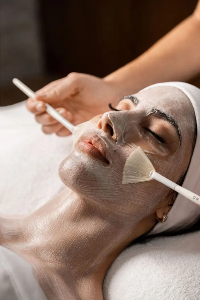 Aplicación de una mascarilla facial con brochas durante una limpieza profunda